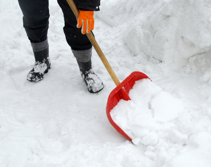 pet sitter wear gloves and boots shoveling snow at a client's home